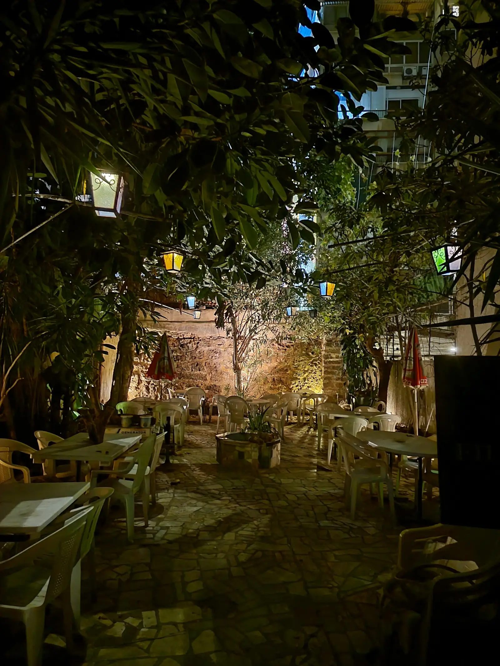 The outdoor seating area at Captain's Cabin at night — tables and chairs under leafy trees strung with lights