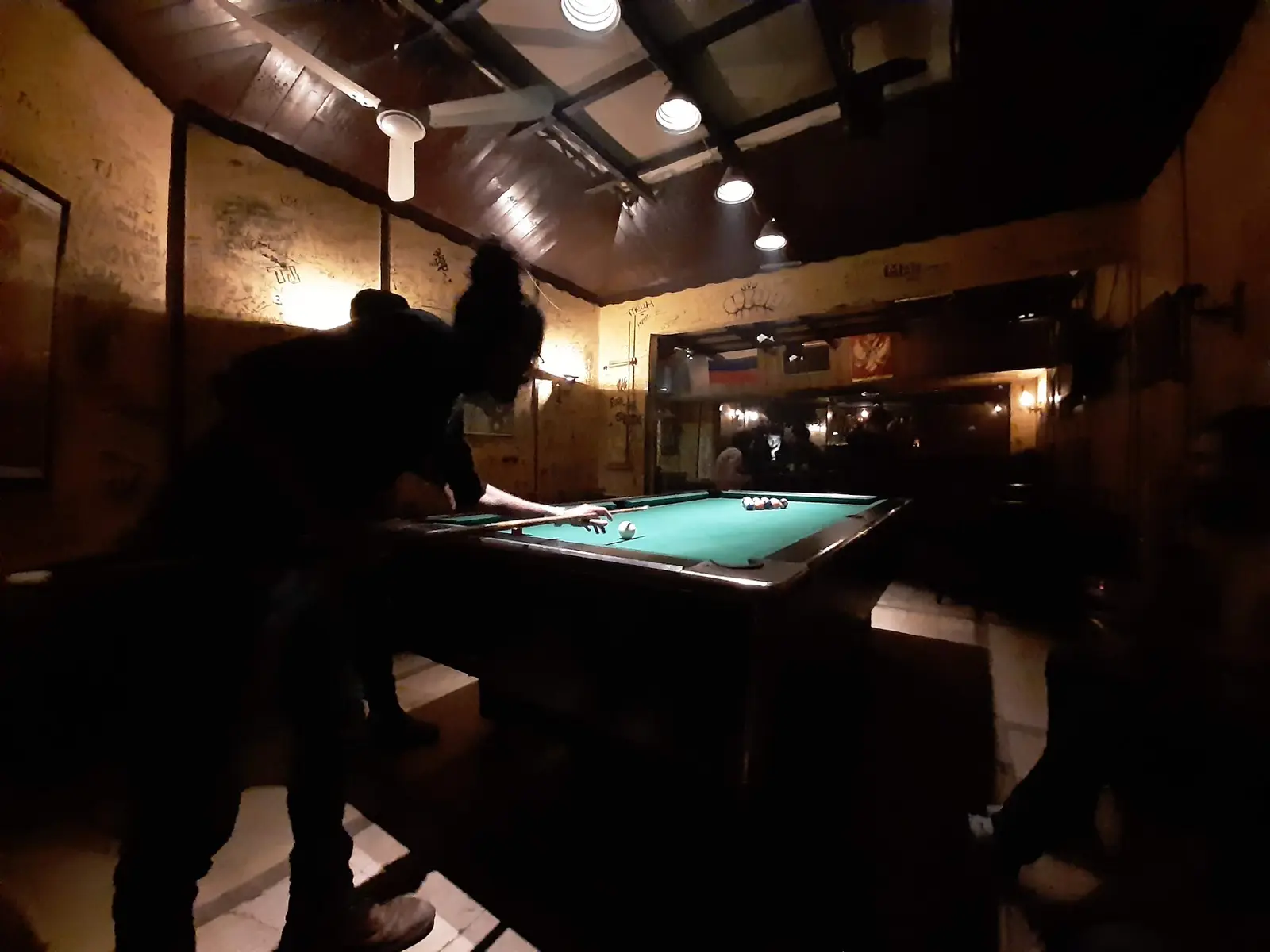 The pool table at the back of Captain’s Cabin, lit from above in a dark room