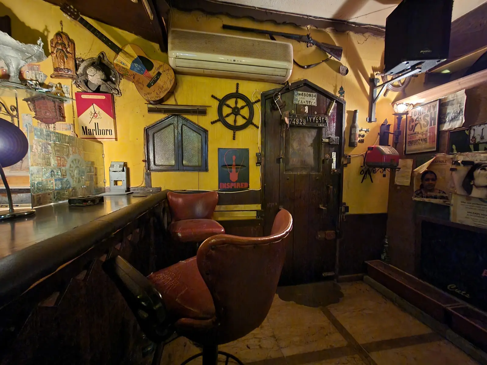 A corner of Captain's Cabin — yellow walls written over in pen, a ship's wheel, framed pictures and a worn leather bench